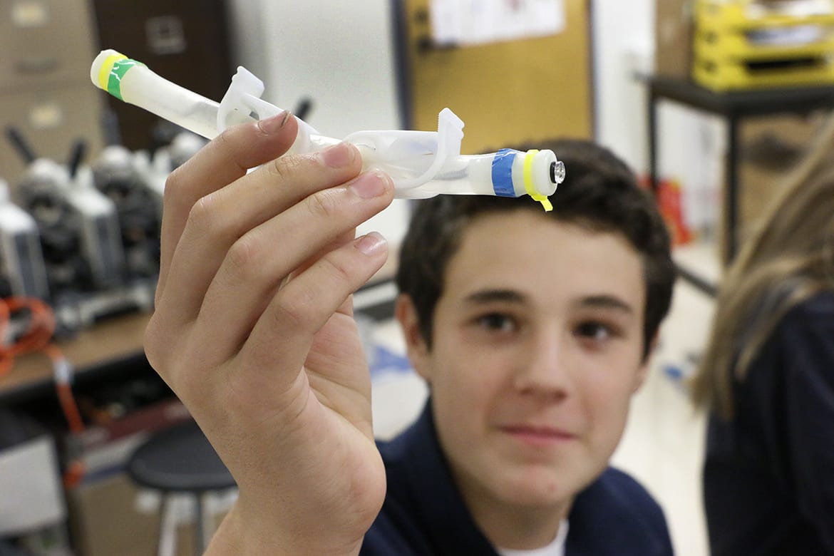 Photo of student holding up small plastic tube.