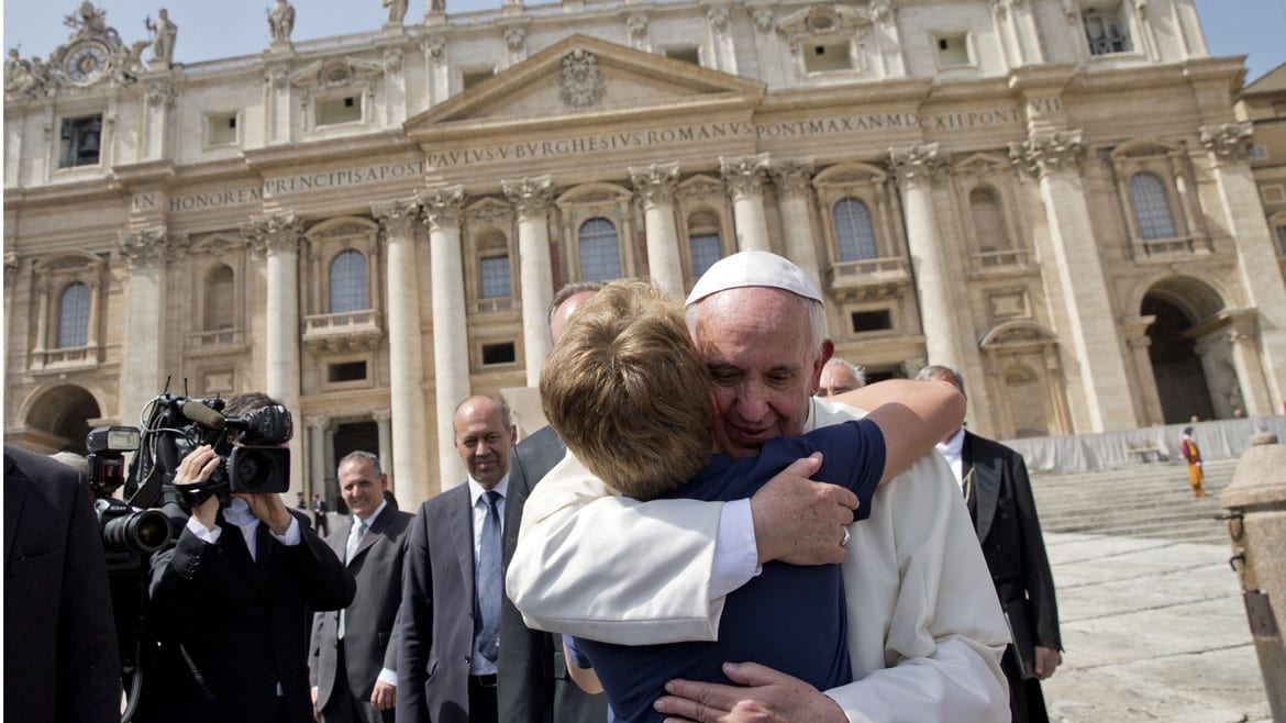 The pope gives a young boy a hug at the vatican