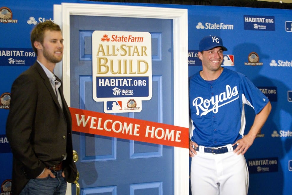 Two baseball players standing near a Habitat for Humanity door