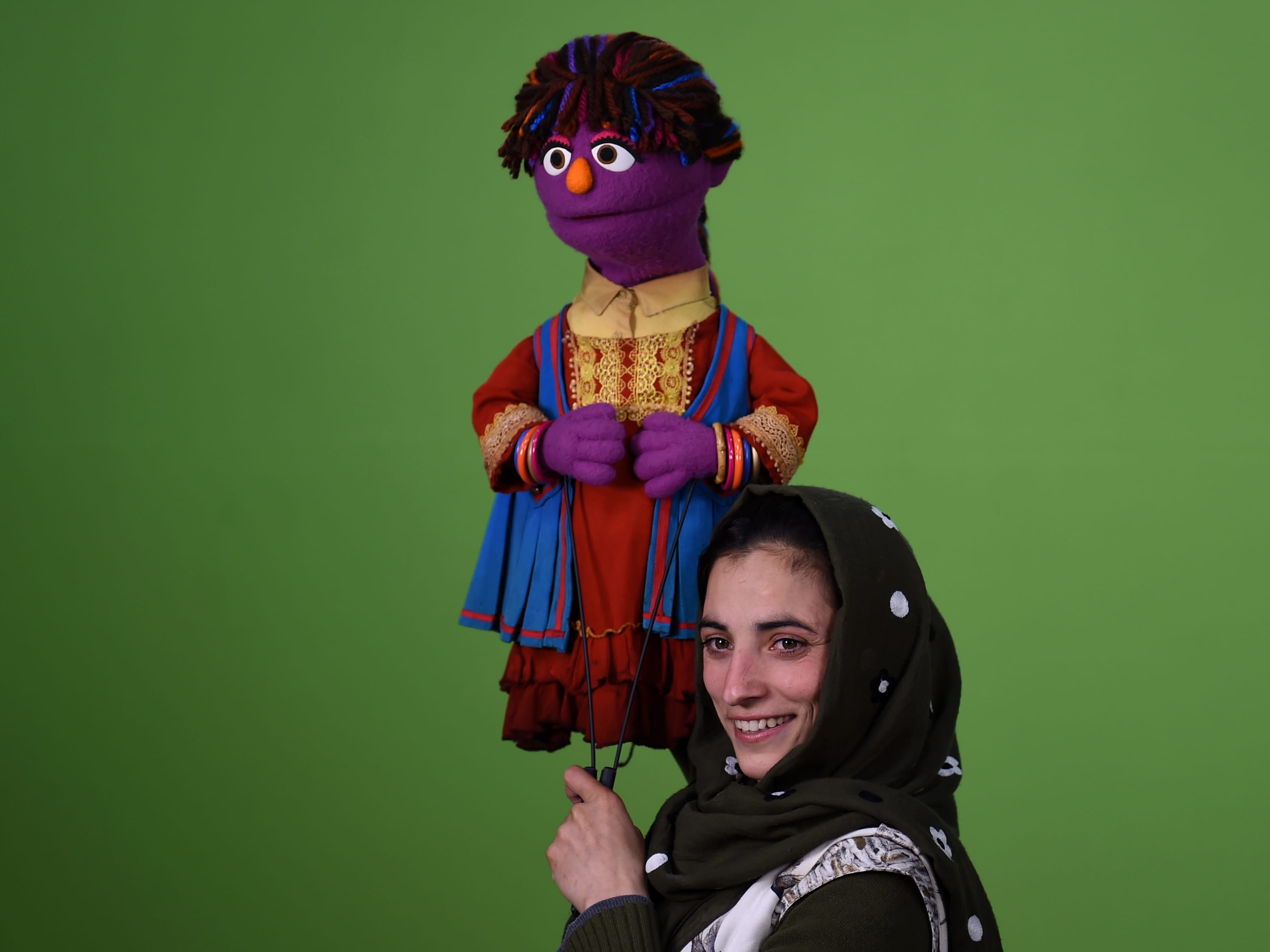 An Afghan woman holding an Afghan puppet for Sesame Street