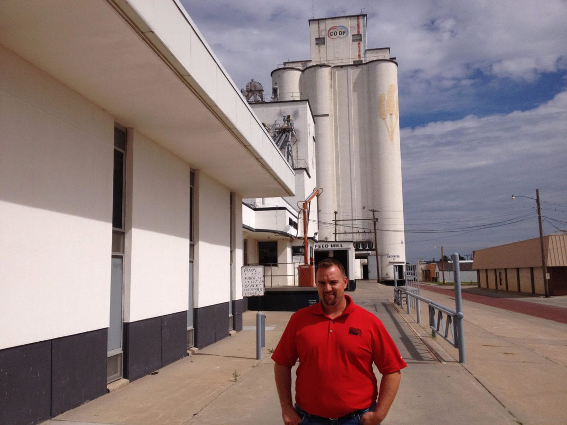 A man standing in front of a grain elevator.