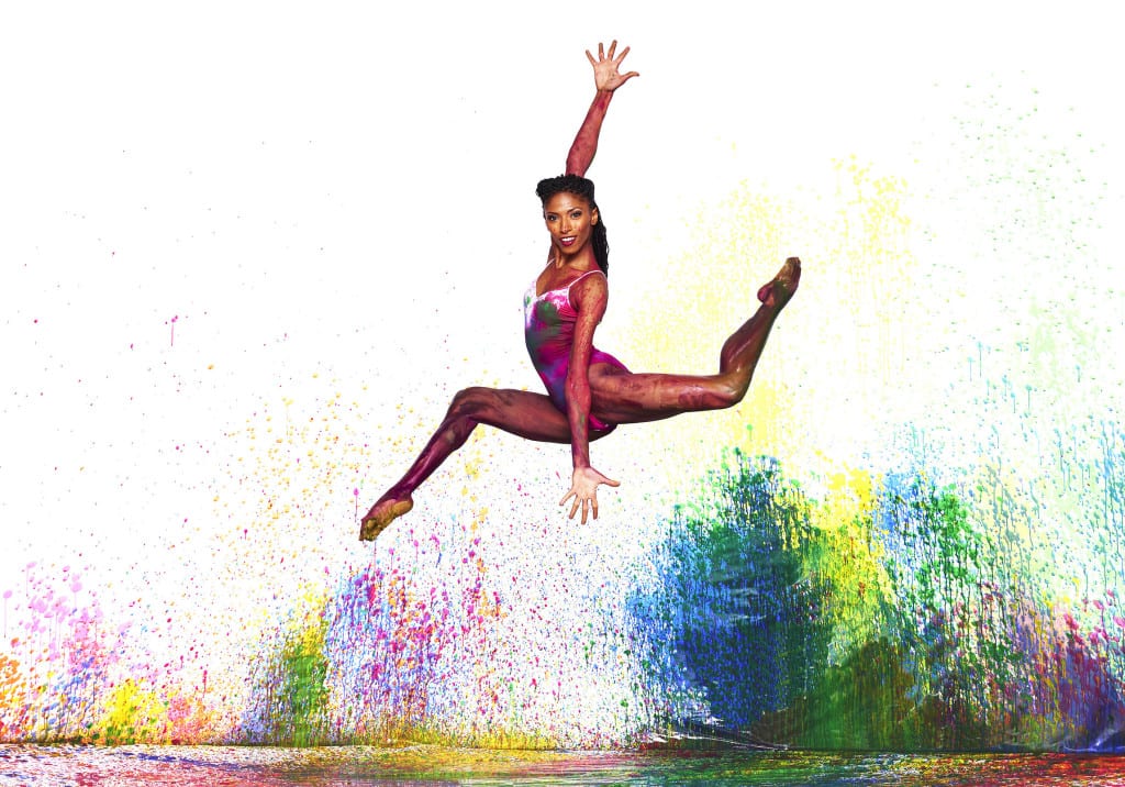 A woman jumping in the air with bright colors behind her.