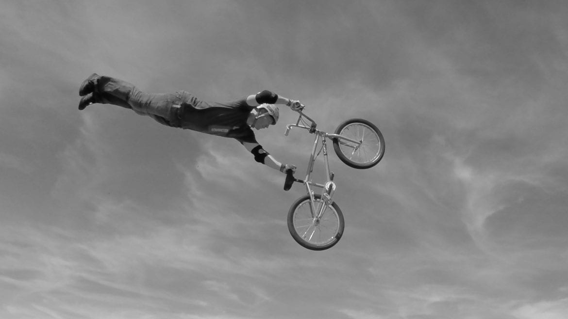 a man flies through the air doing stunts on a bike.