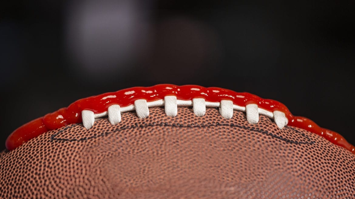 a football with ketchup on the laces