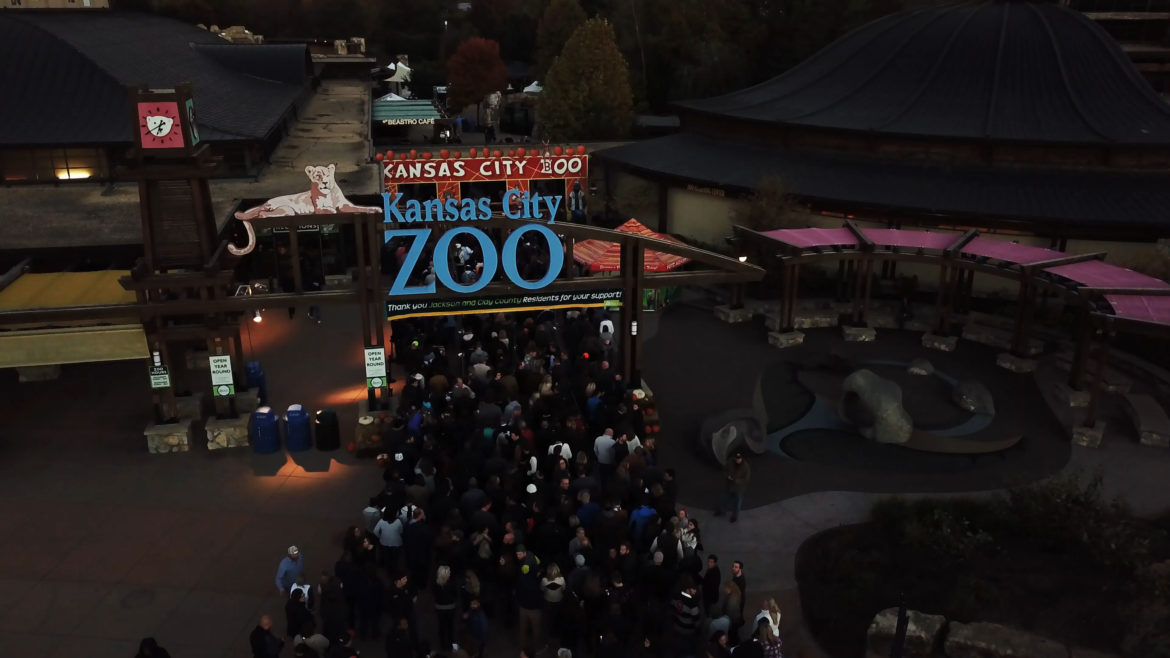 A crowd enters the zoo's front gate.