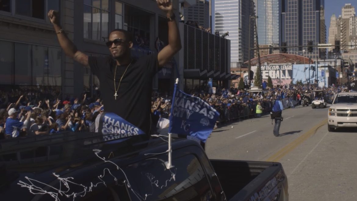 Shortstop Alcides Escobar lifts his arms in celebration riding in the World Series Parade.