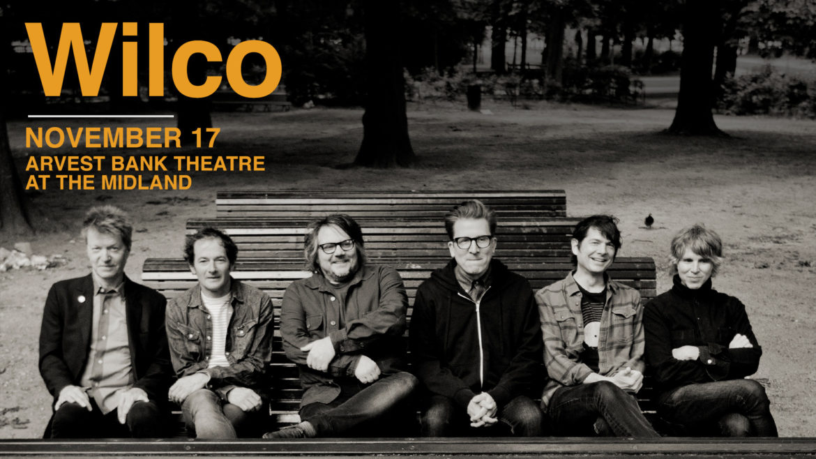 Members of Wilco sitting on a bench. Wilco is playing at The Midland November 17.
