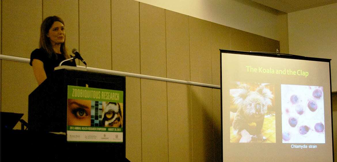 Kathryn Bowers stands at a podium in front of presentation projected on a screen.