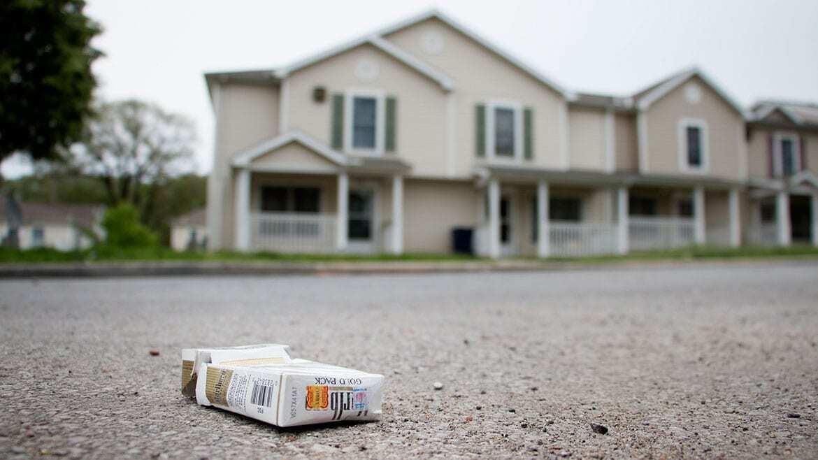 Pack of cigarettes on street with houses in background