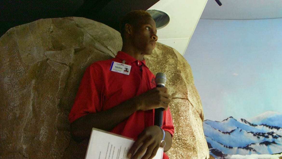 Green Works KC student Keylen Madge speaking into microphone while giving "Penguin Chat" at the KC Zoo.