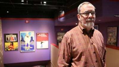 Man stands next to vintage movie posters.