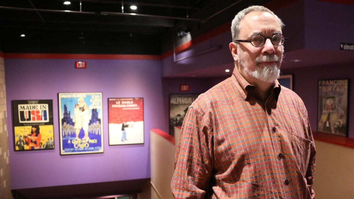 Man stands next to vintage movie posters.