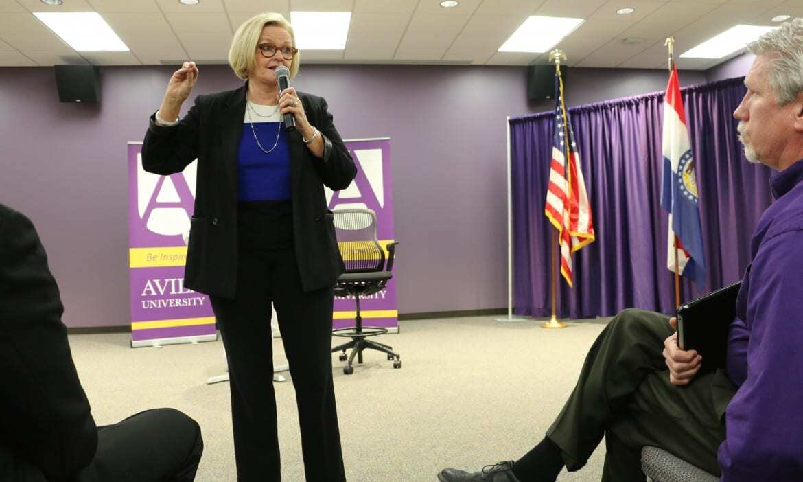 Woman speaks to crowd in conference room.