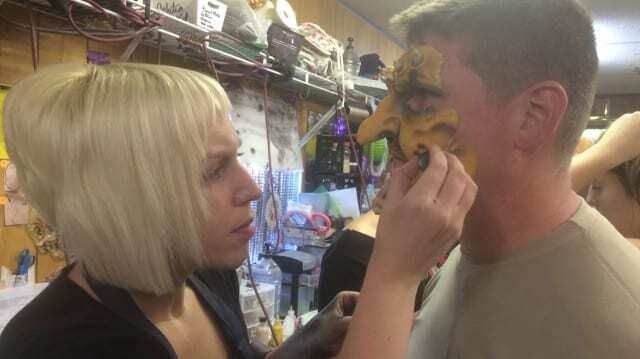 Lindsey Doolittle, makeup artist and elementary school art teacher, is spending her Halloween-season weekends in the makeup trailer for Worlds of Fun's Haunt. She's pictured here applying a mask to Mark Farrar, one of the "screamsters" for Haunt. (photo by Caitlin Cress/Hale Center for Journalism)