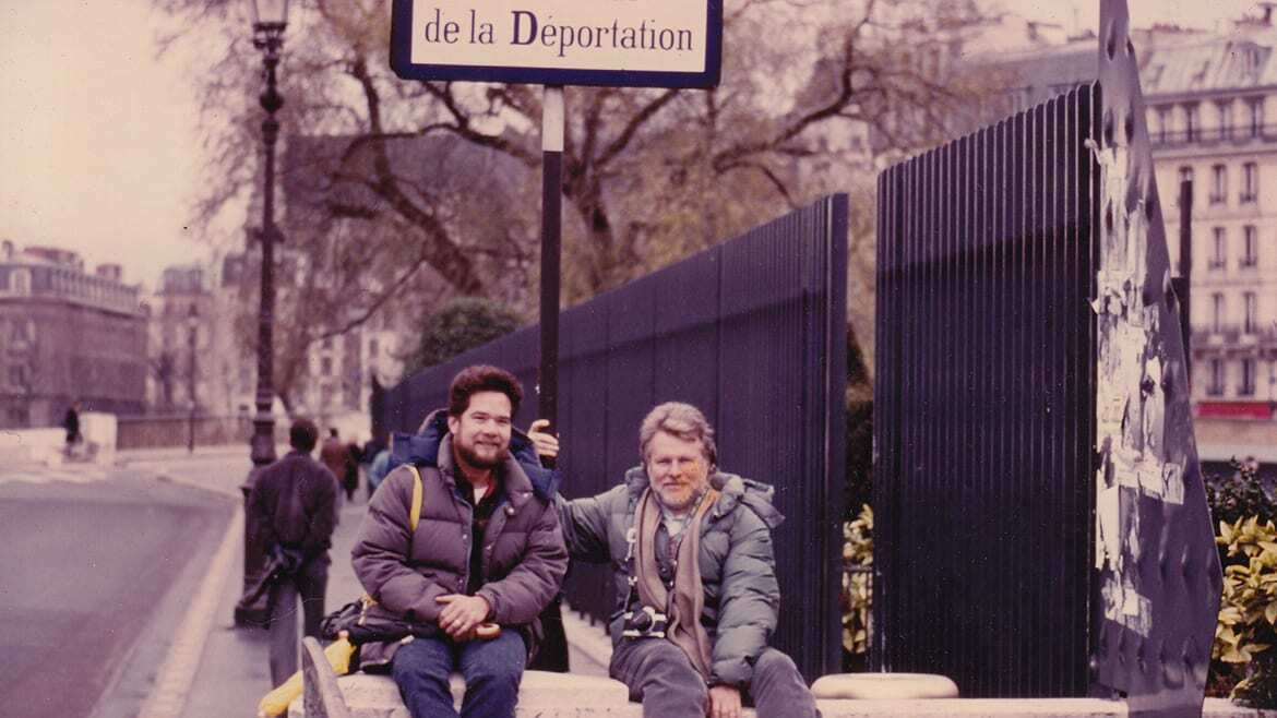 Old photo of two men posing for a picture on a street.