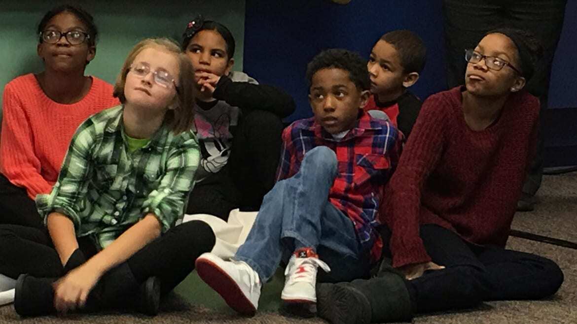 Children o the floor listening to announcement.