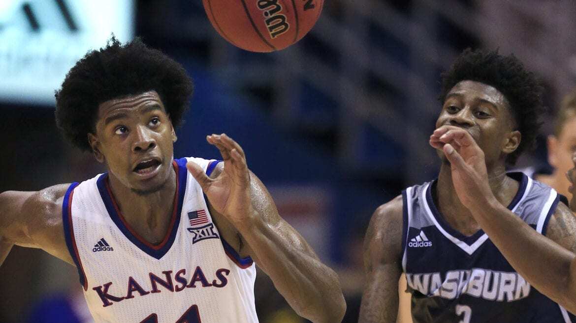 Two basketball players running for the ball.