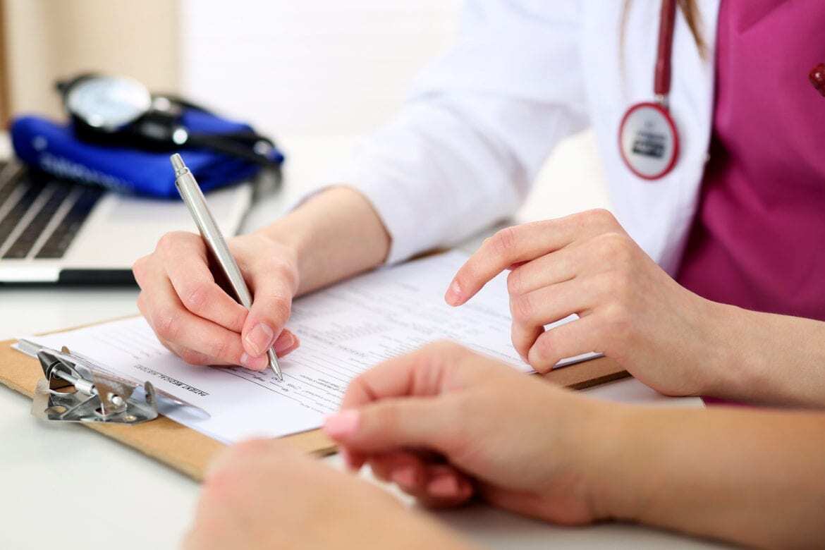 A doctor writing on a medical chart.