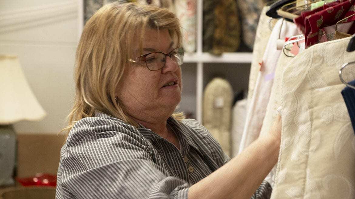 Sheryl Raineri arranges clothing at the Manor Thrift Shop in Liberty, Missouri.