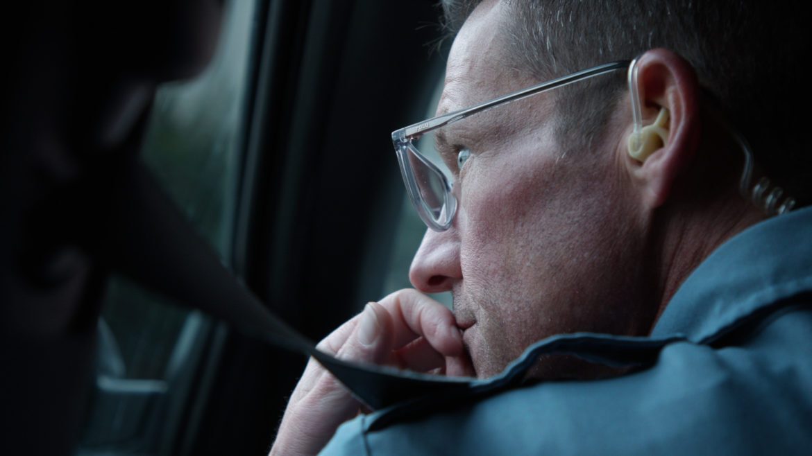 A Kansas City police officer peers out of the window of his car while on patrol.
