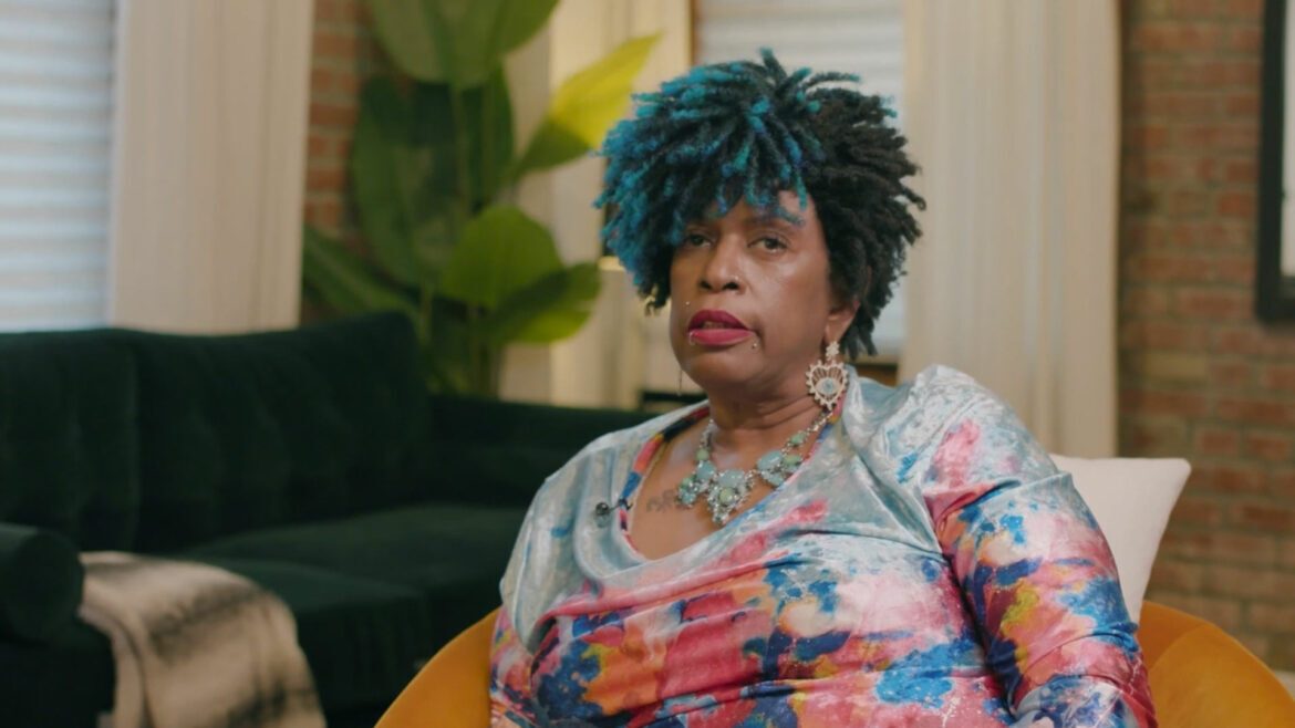 Woman with blue hair and colorful shirt sitting