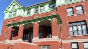 A brick building with Tudor styling and green trim on top.