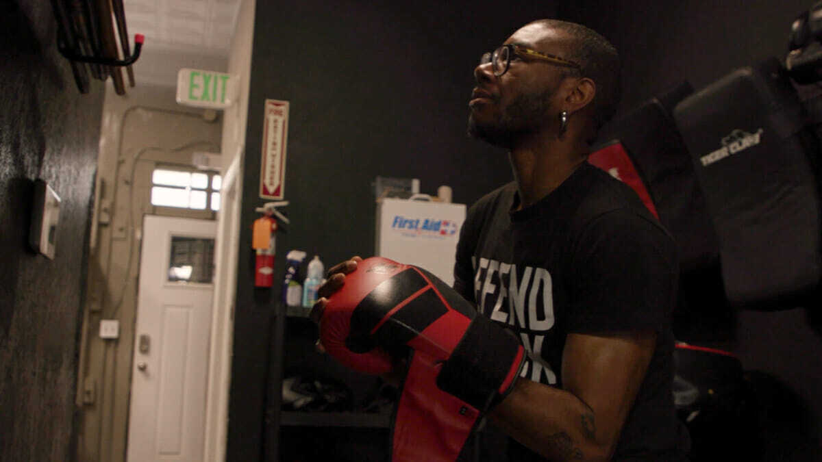 Person in glasses with boxing gloves in dark room