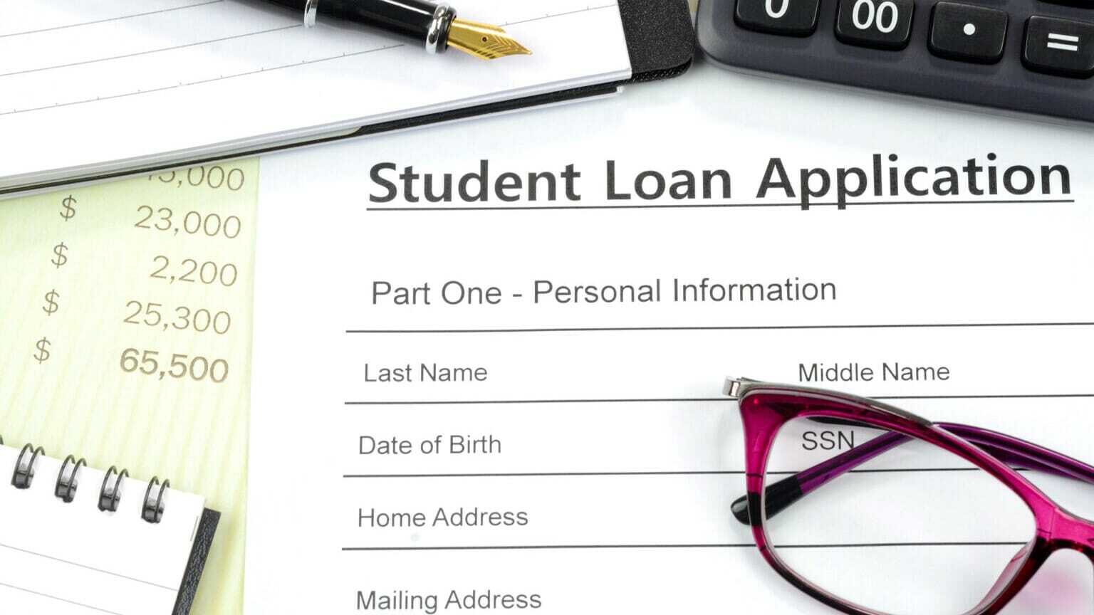 Applying for student loan. Filling up the loan form with calculator, pen, note pad on the desk