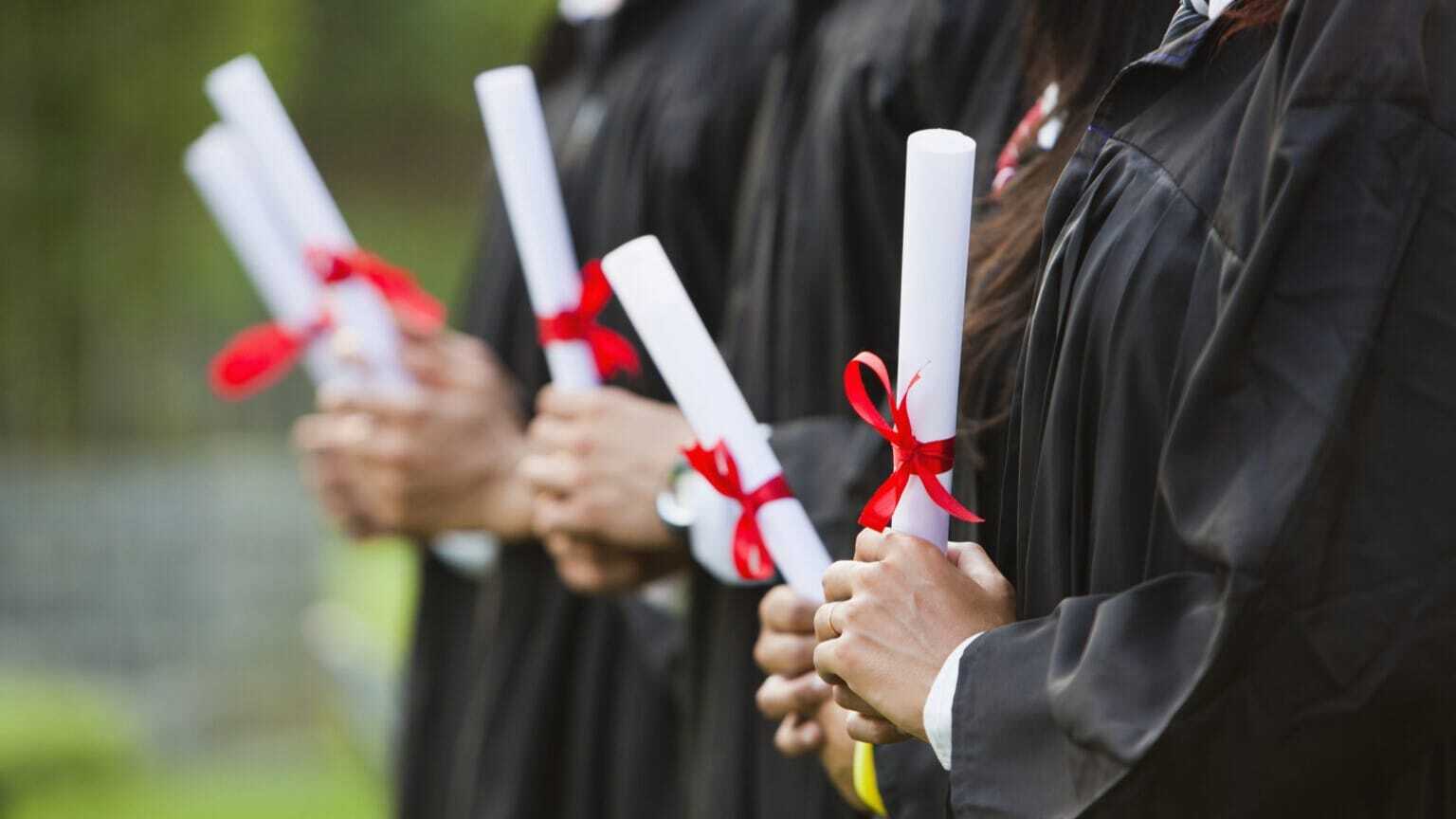 College students holding diplomas at graduation ceremonies.