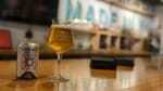 Rizoma beer in a glass and can on a bar.