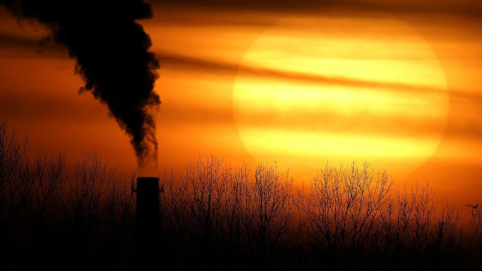 In this Feb. 1, 2021, a smokestack from Evergy's Hawthorn coal-fired power plant is silhouetted against the setting sun in Kansas City.