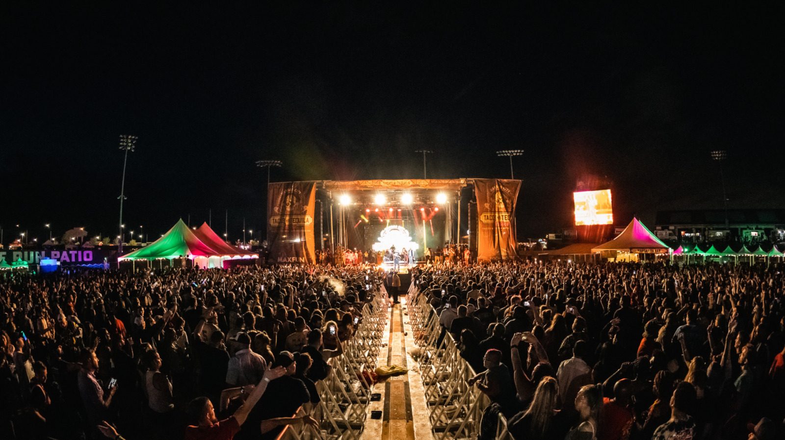 A stage lit up at night with a large crowd.