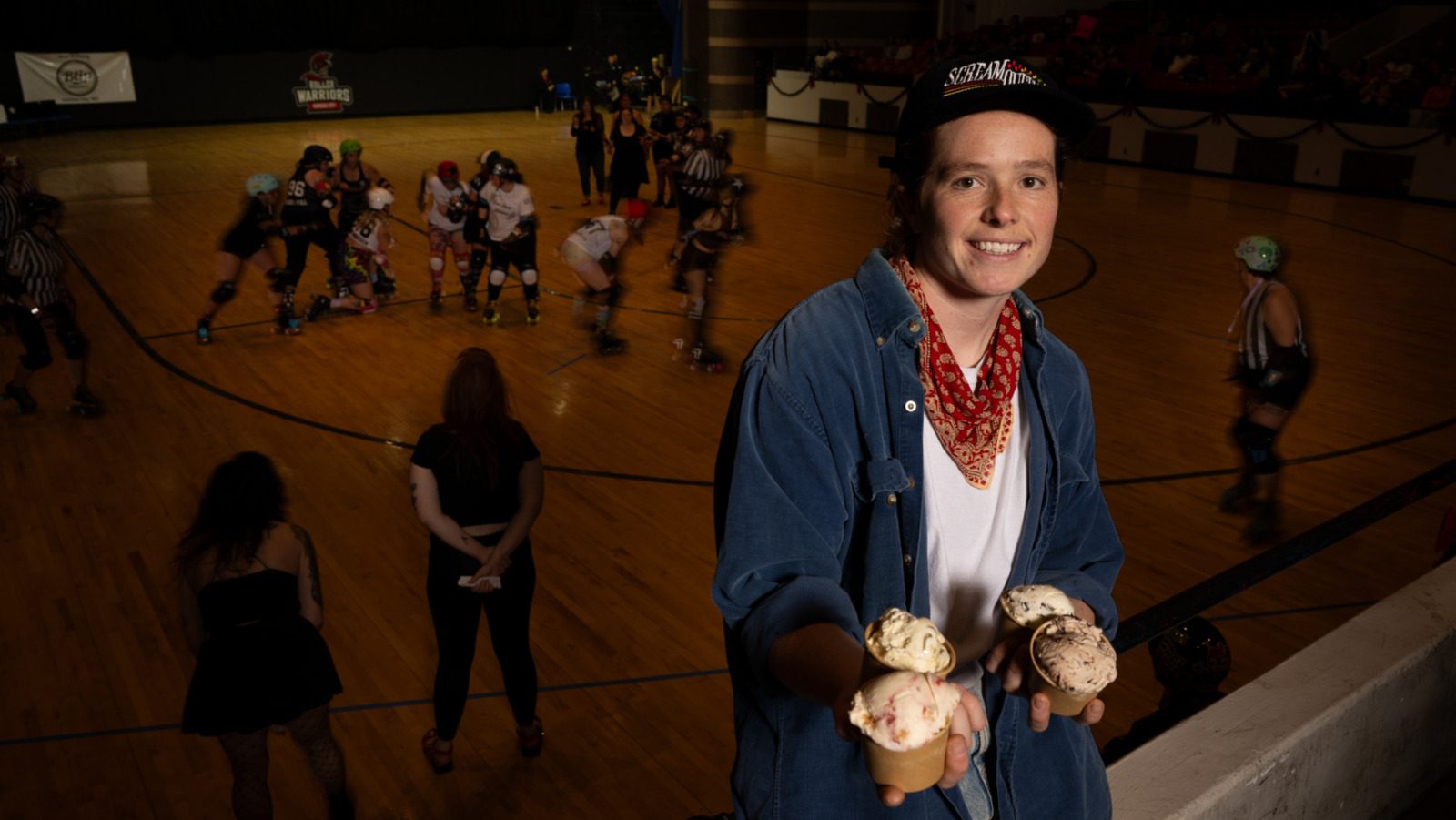 With a roller derby bout underway, Zoe Mays of Scream Queens vegan ice cream, a resident concession partner at the event, posed with the four special flavors she developed in partnership with the teams. The Kansas City Roller Warriors bout was at Memorial Hall in Kansas City, Kansas on Dec. 6, 2025. (Todd Feeback | Flatland)