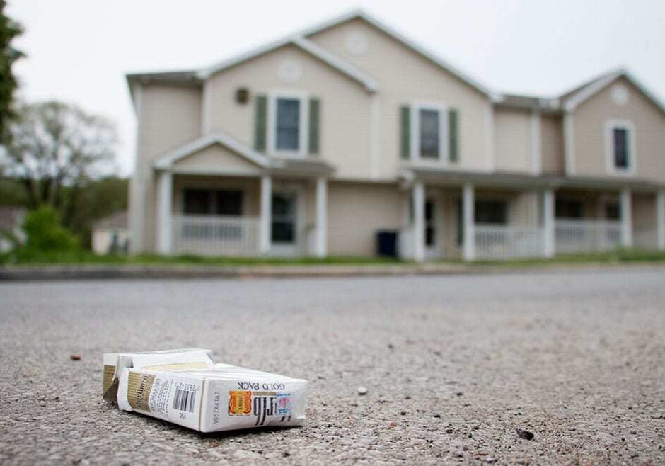 Pack of cigarettes on street with houses in background