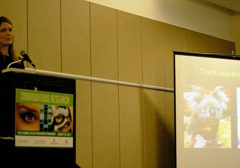 Kathryn Bowers stands at a podium in front of presentation projected on a screen.