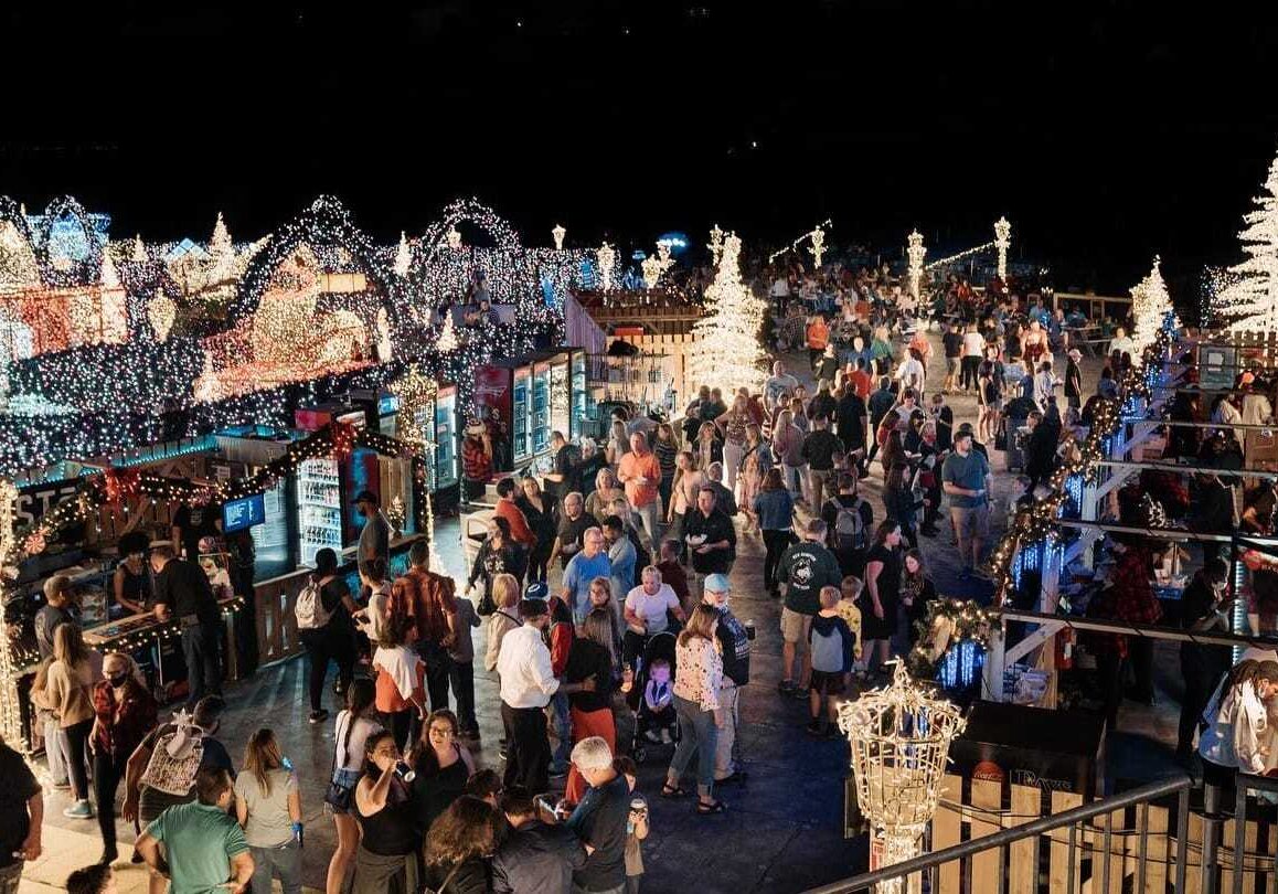 A crowd of people move through a holiday lights maze.