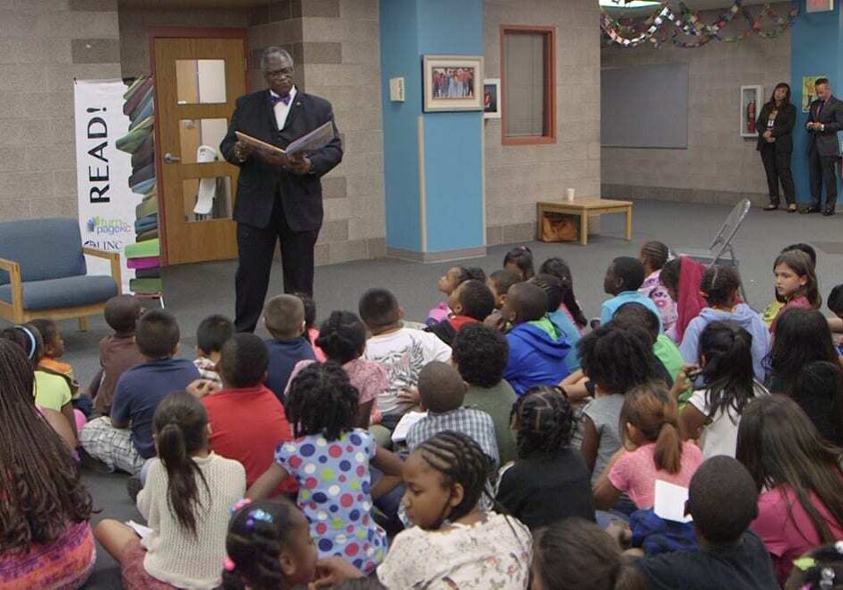Kansas City, Missouri Mayor Sly James stands and reads in front of group of students sitting on the floor.