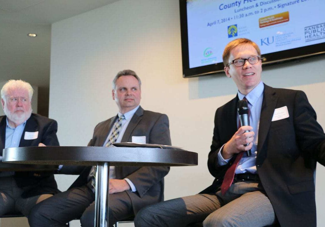 Three officials discussing county health rankings in Kansas