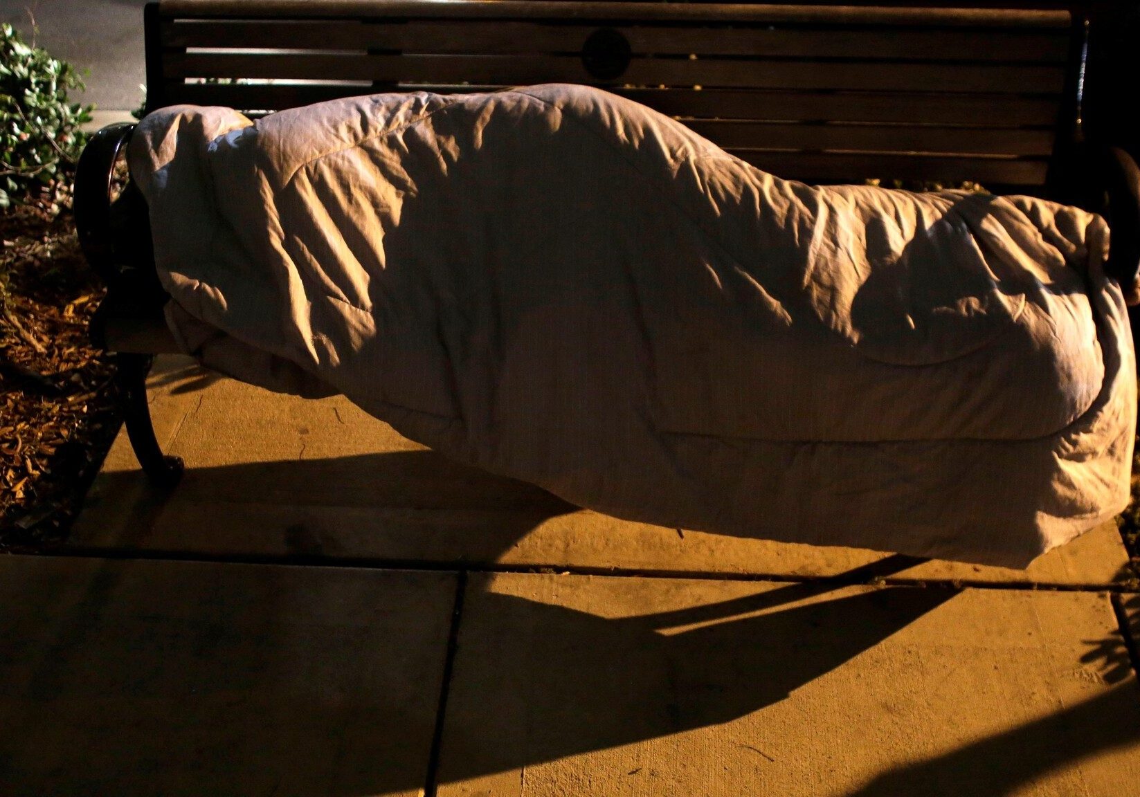 A homeless person sleeps on a bench as volunteers and homeless outreach officials walk in the area during the Point In Time Homeless Census in Miami.