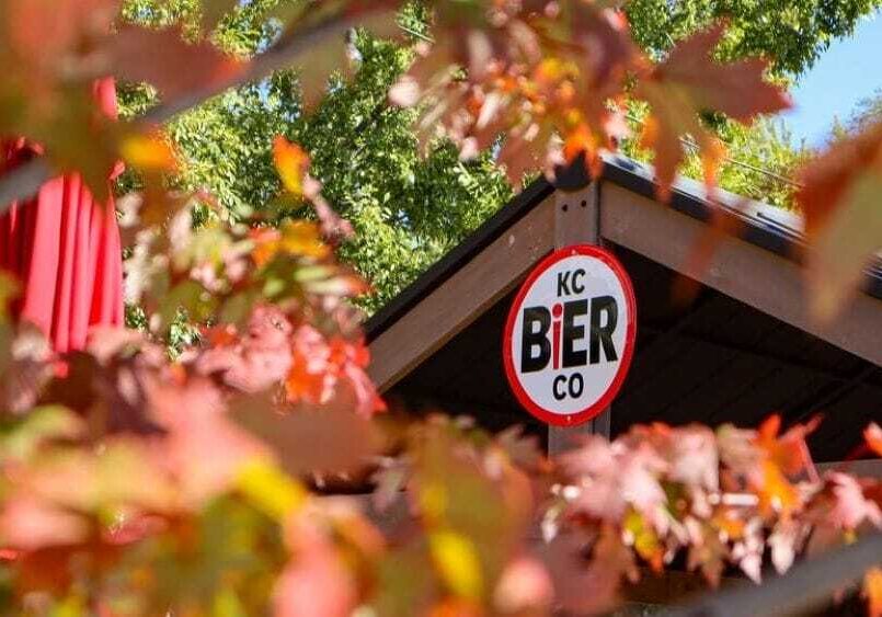 KC Bier Co. sign among colorful fall leaves.