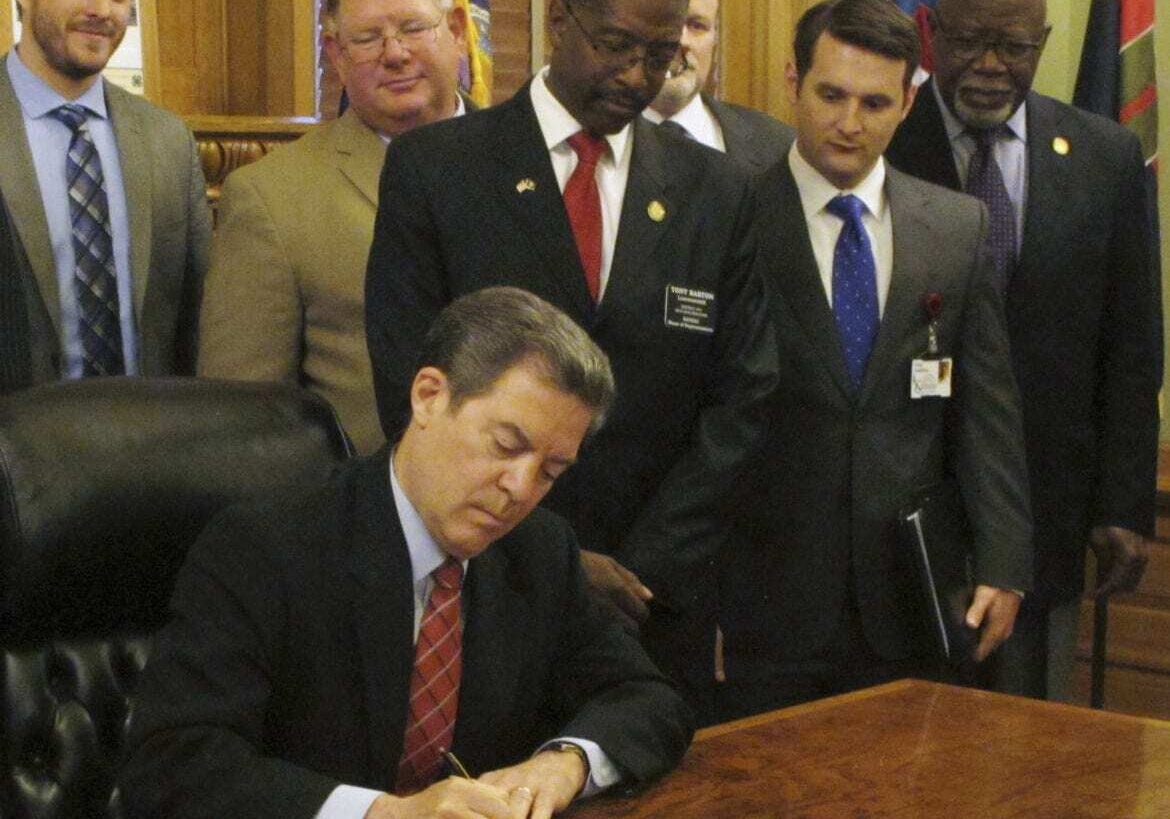 Kansas Gov. Sam Brownback signs legislation tightening the state's lifetime limits on cash assistance and making other changes in welfare policies, Monday, May 16, 2016, at the Statehouse in Topeka, Kan. Brownback says such changes help move people out of poverty and government dependence and into the work force. (AP Photo/John Hanna)