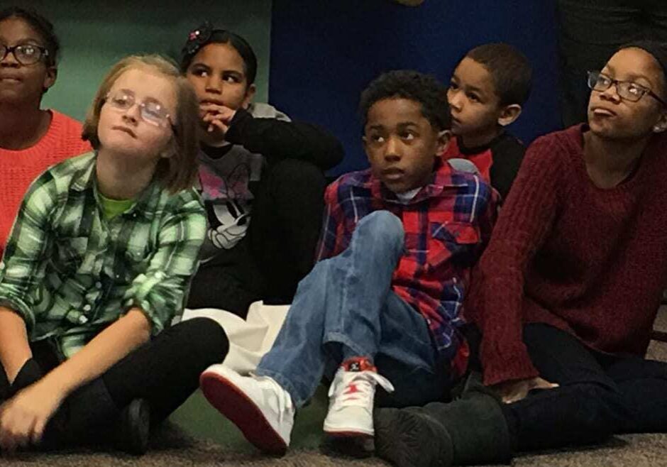 Children o the floor listening to announcement.