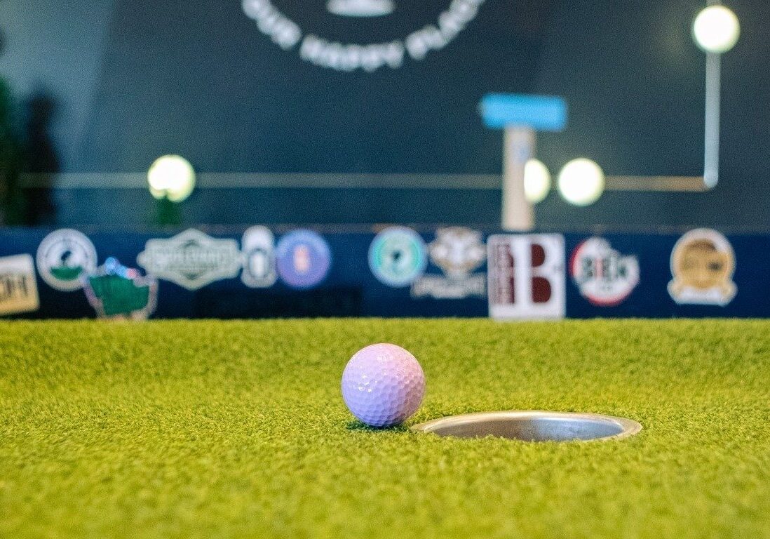 A golf ball near a hole on a mini golf course