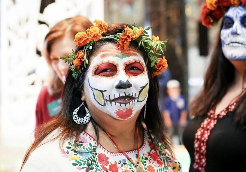 A woman poses in full calavera face paint.