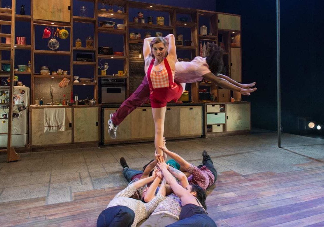 A woman being suspended in the air by other performers.