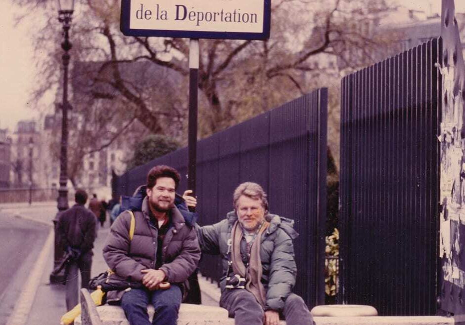Old photo of two men posing for a picture on a street.