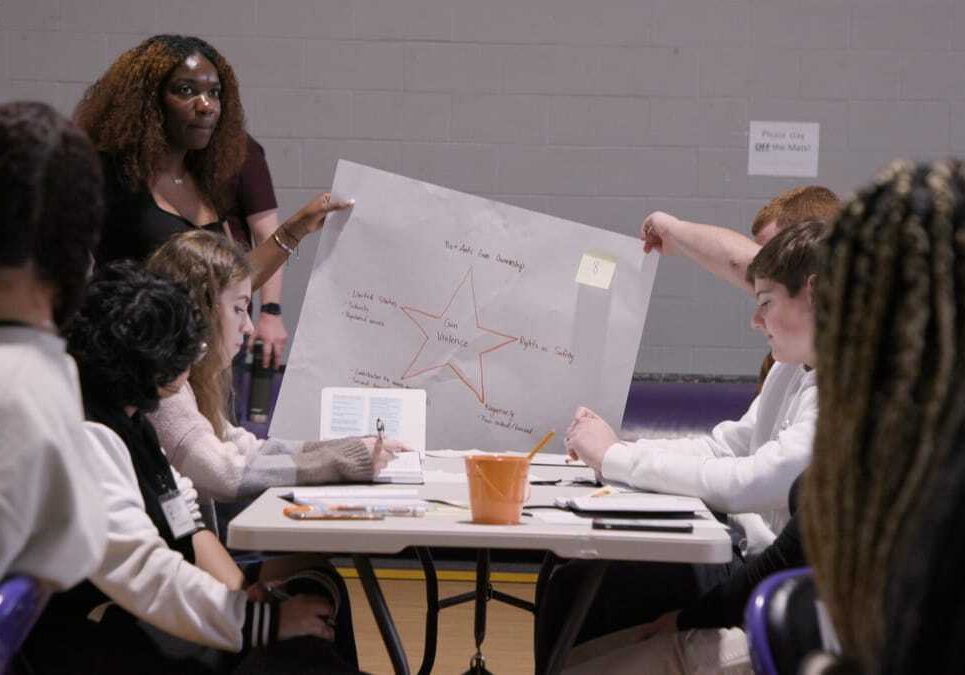 Students hold up a poster with a star in the middle and notes written all around it.