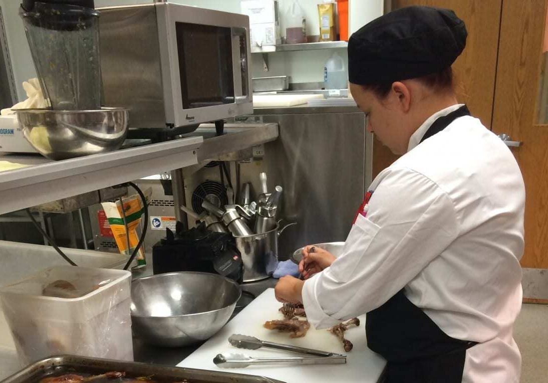 Senior Sarah Miller prepares the duck confit for Wednesday's opening night at Broadmoor Bistro. (photo by Caitlin Cress/The Hale Center for Journalism) 