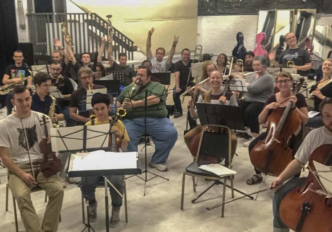 A crowd of musicians playing orchestral instruments.