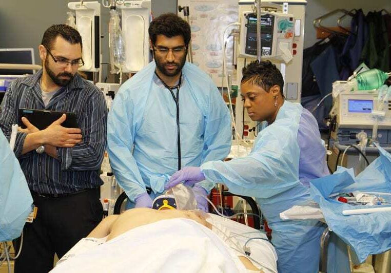 Chris Sharkey (left), a language interpreter, Dr. Ravi Patel, an emergency medicine resident and Felicia Davis, a respiratory therapist, attend to an emergency room patient at Truman Medical Centers.